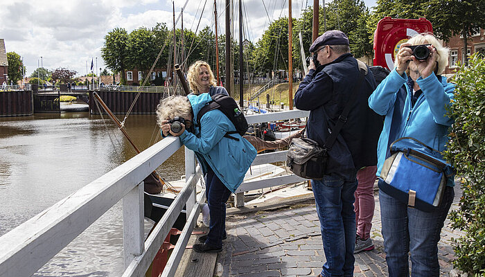 Vier Personen stehen am Wasser und suchen Motive mit Spiegelreflexkameras.