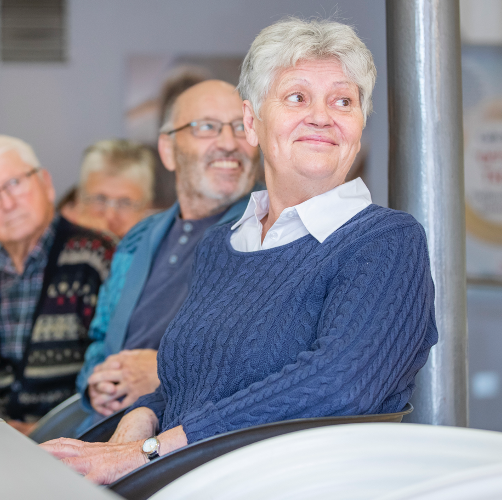 Seniorinnen und Senioren sitzen lächelnd an einem Tisch