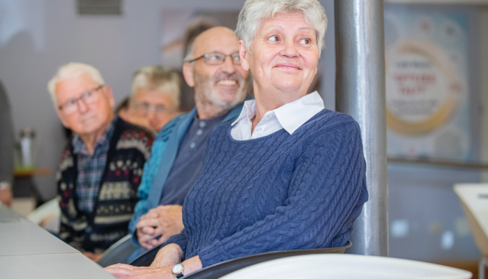 Seniorinnen und Senioren sitzen lächelnd an einem Tisch