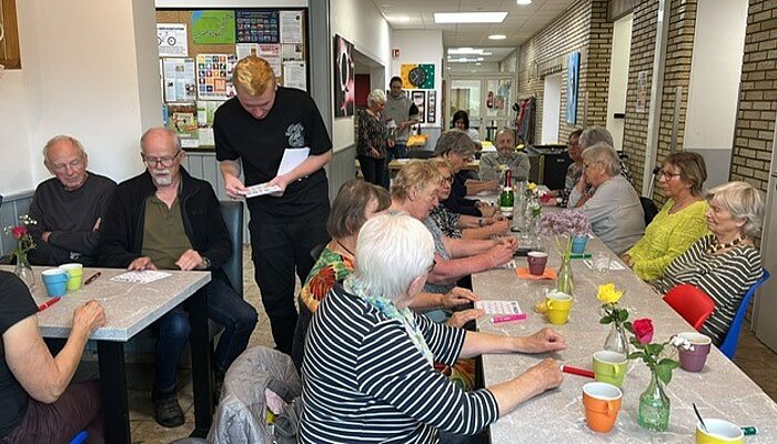  Besucher*innen warten auf das Austeilen der Bingokarten