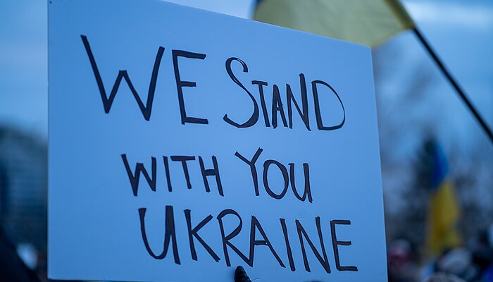 Pappschild mit der Aufschrift "We stand with you Ukraine"