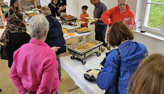 Menschen stehen an einem Buffet und nehmen sich Essen