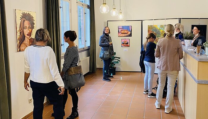 Mehrere Menschen schauen sich eine Kunstausstellung an