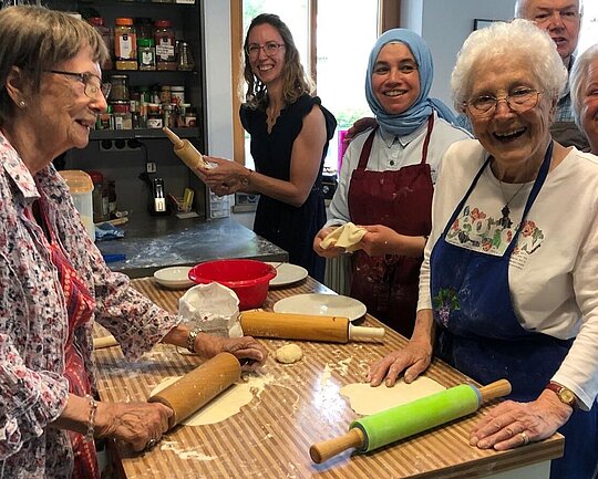 Nachbarschaftshilfe Taufkirchen Unterhaching eV Gruppe von Menschen verschiedenen Alters, die in einer Küche stehen und gemeinsam backen.
