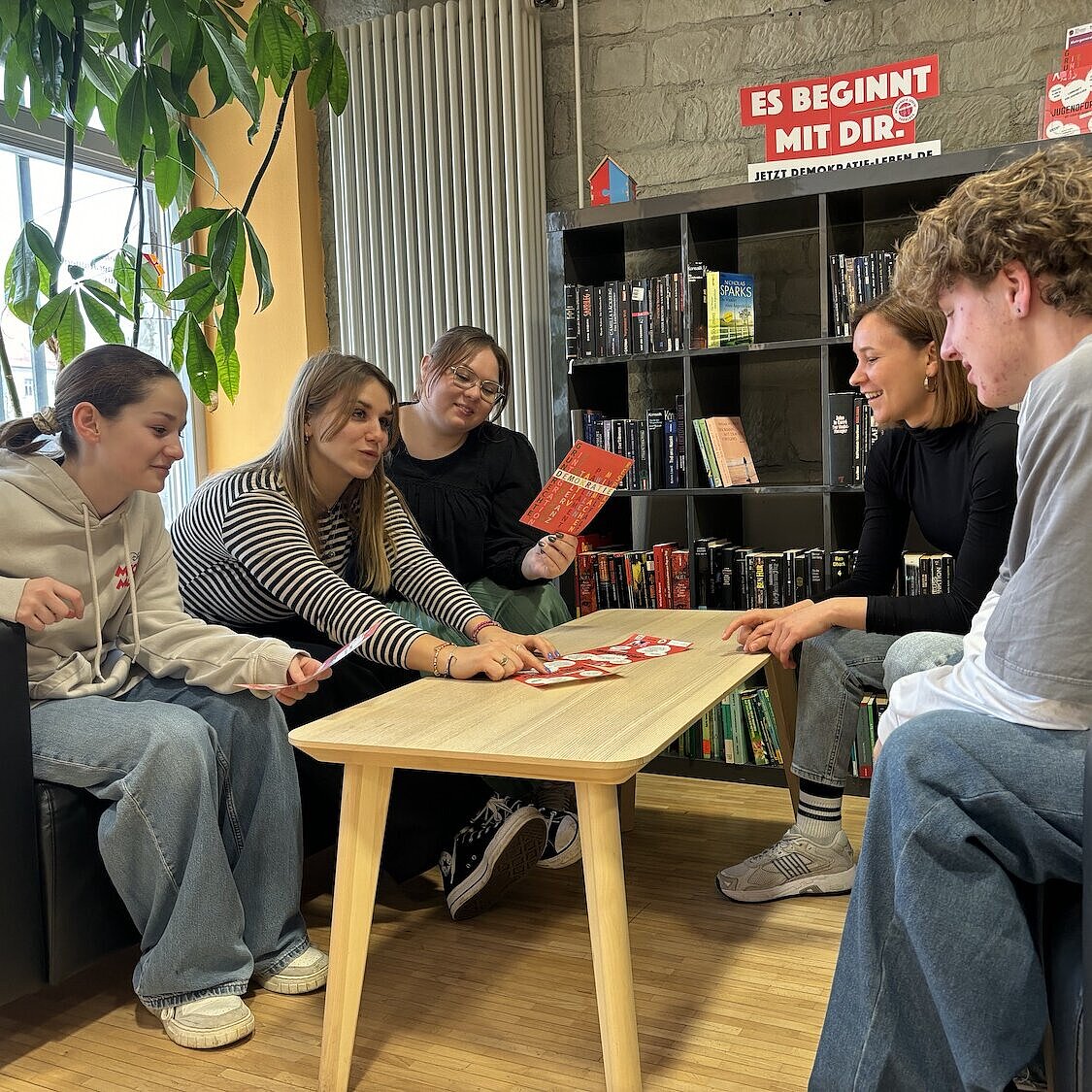 Fünf Jugendliche sitzen an einem Tisch und sprechen miteinander