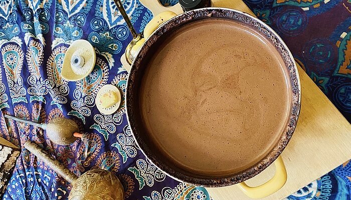 Eine Schüssel mit Cacao und Zubehör stehen auf einer bunten Decke.