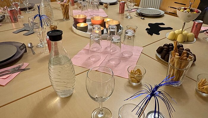 Ein gedeckter Tisch mit Tellern, Gläsern und bunter Dekoration