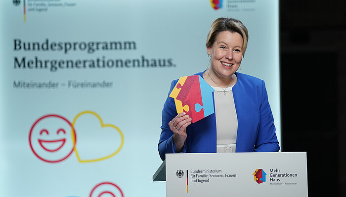 Bundesfamilienministerin Franziska Giffey steht am Rednerpult mit dem MGH-Häuser-Logo in der Hand