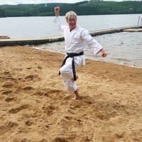 Ulrich Schulze macht im Karateanzug eine Karatepose am Strand