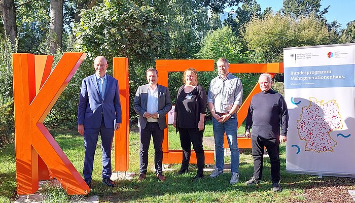 Vor dem Wort "Kiez" stehen (von links nach rechts): Michael Brand (Parlamentarischer Staatssekretär), Martin Schaefer (Bezirksbürgermeister Lichtenberg), Anne Stöckmann (stellv. Geschäftsführerin Kiezspinne, Koordinatorin MGH), Christian Gridel (Geschäftsführer Kiezspinne), Andreas Svojanovsky (1. Vorsitzender des Vorstands Kiezspinne)