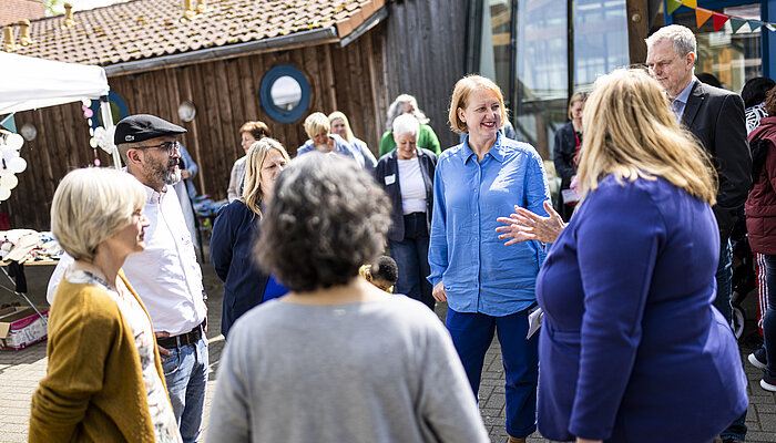 Ministerin Lisa Paus unterhält sich draußen mit verschiedenen Menschen. 