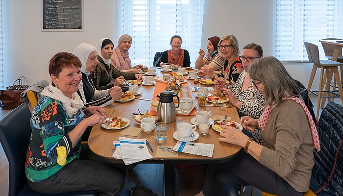 Mehrere Frauen sitzen an einem Tisch und frühstücken