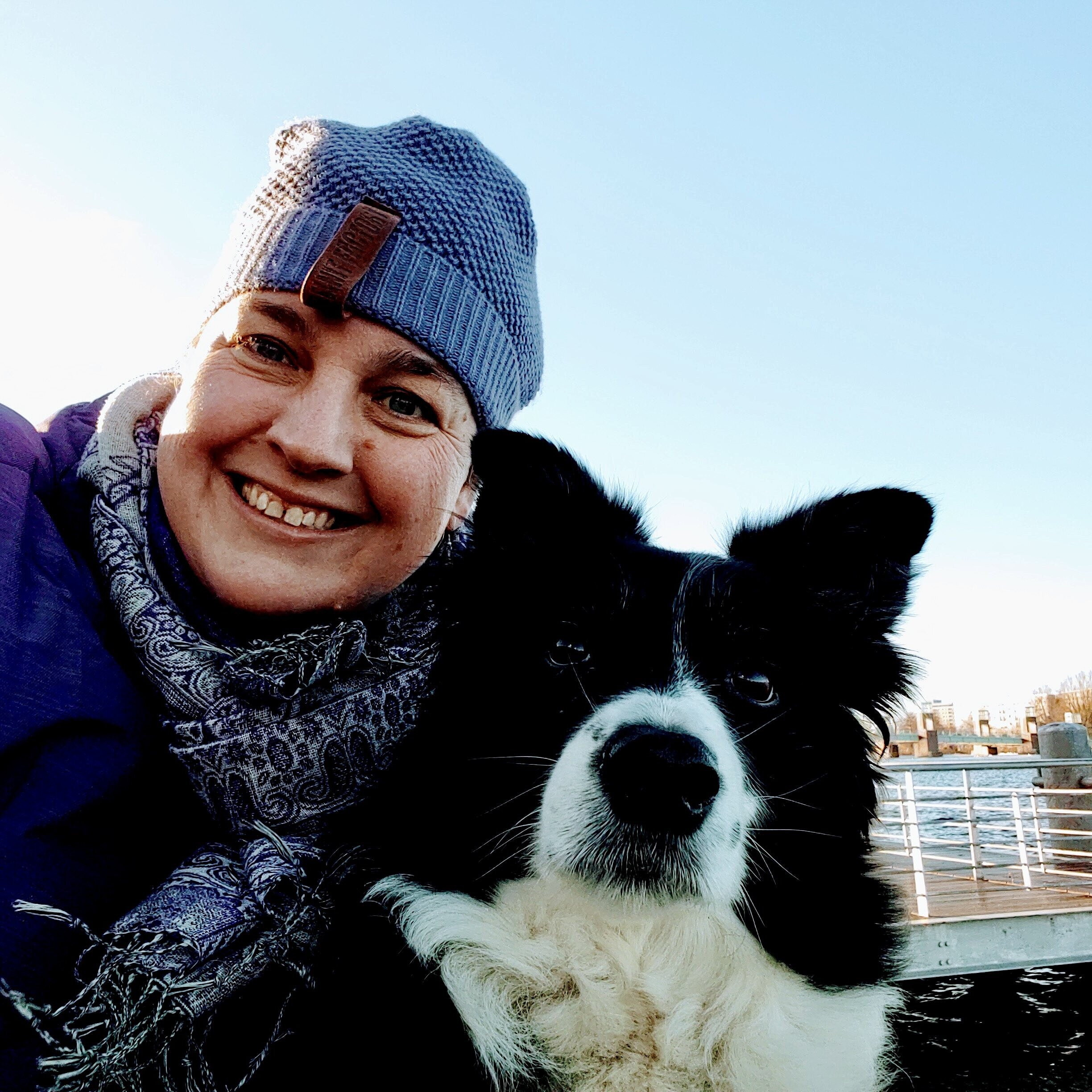 Christina Meyer lacht in die Kamera, neben ihr sitzt ihr Hund Curly 