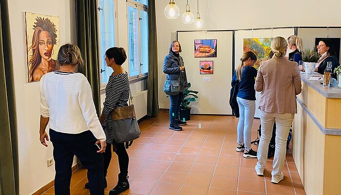 Mehrere Menschen schauen sich eine Kunstausstellung an.